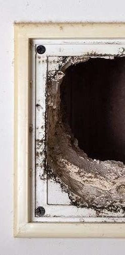 An air vent opening thick with accumulated dust and debris